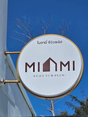 A circular sign with the text 'MIAMI seaviewPLUS' and a house icon, mounted on a building.