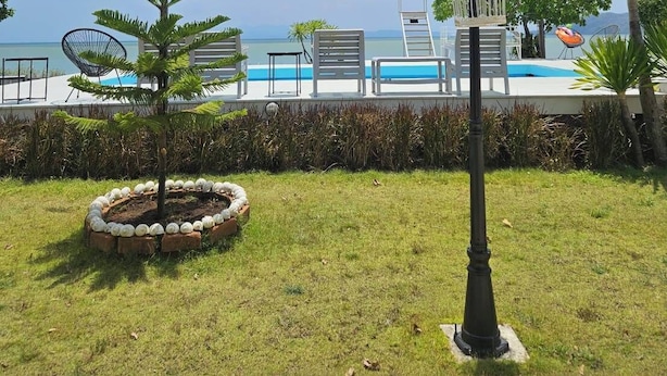 A poolside area with lounge chairs, a lamp post, and a view of the sea. - Miami Seaview (La-ngu)