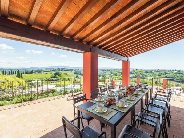Un espacio de comedor al aire libre con vistas a un viñedo y colinas.