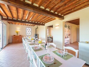 Un comedor con una mesa larga dispuesta para una comida, vigas de madera en el techo y una chimenea.
