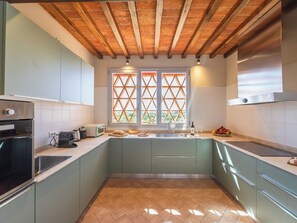 Une cuisine avec un plafond en bois, une fenêtre ornée d’un motif en treillis et un évier.