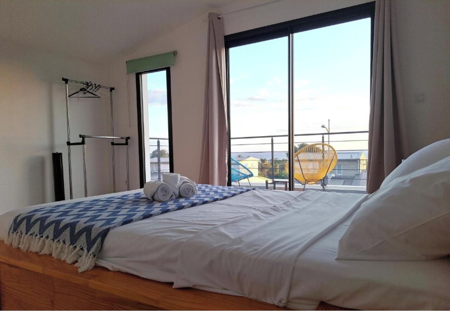 Habitació d'hotel amb un llit, una finestra amb vistes, una cadira i un estenedor.