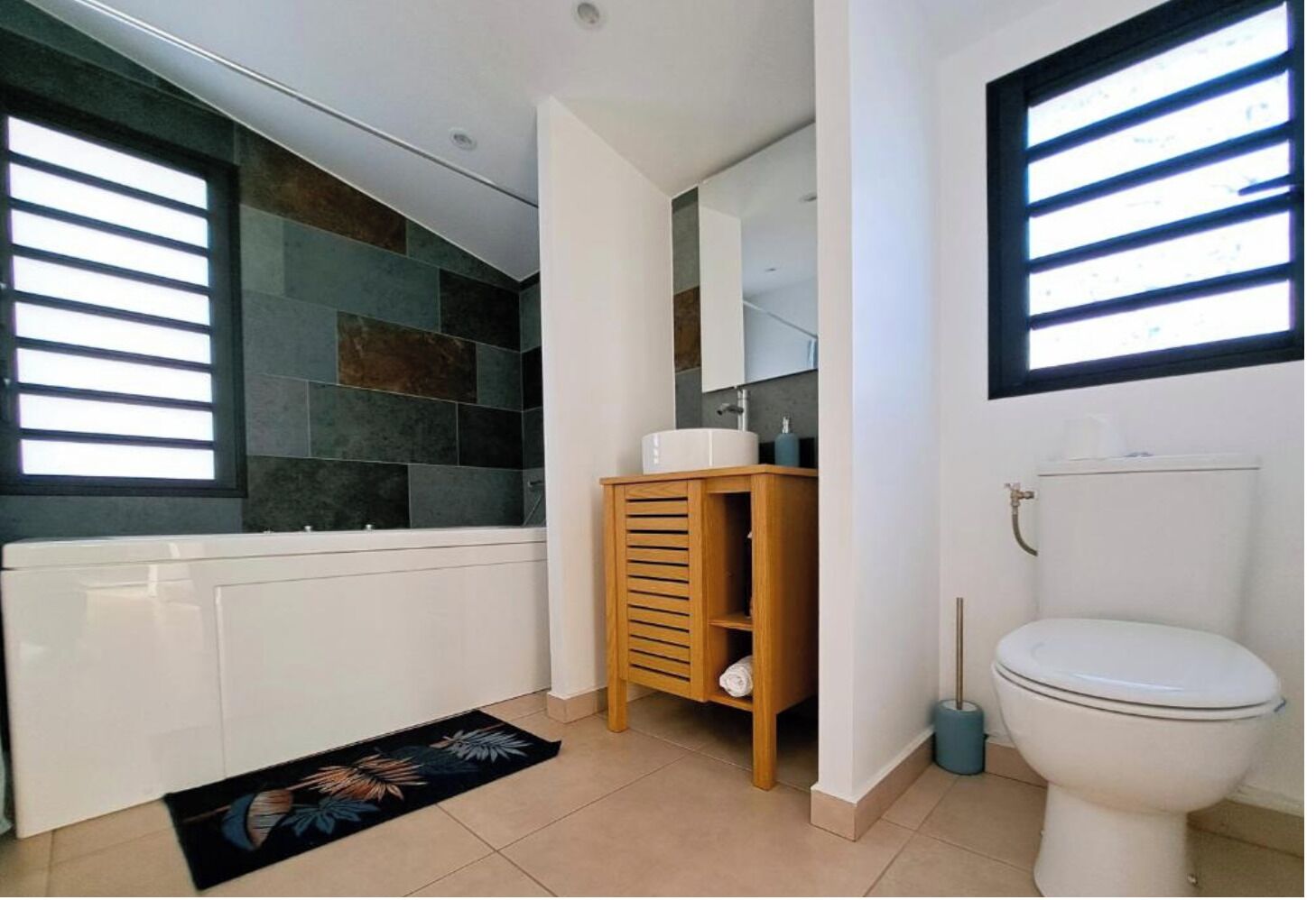 Une salle de bain avec une baignoire, des toilettes et un meuble-lavabo en bois.