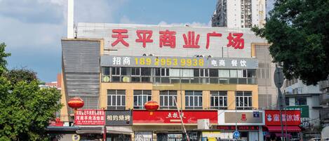 A commercial building with multiple storefronts, including a prominent red sign for a business.