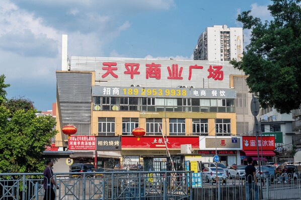 A commercial building with multiple storefronts, including a prominent red sign for a business. - YueZhi Hotel Guangzhou East Station (Guangzhou)