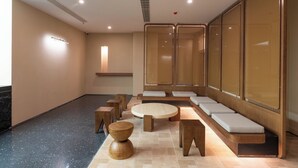 A modern waiting area with seating, a round table, and a small wooden stool. - YueZhi Hotel Guangzhou East Station (Guangzhou)