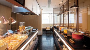A buffet area with various food stations, a seating area, and a view of the city through large windows. - YueZhi Hotel Guangzhou East Station (Guangzhou)