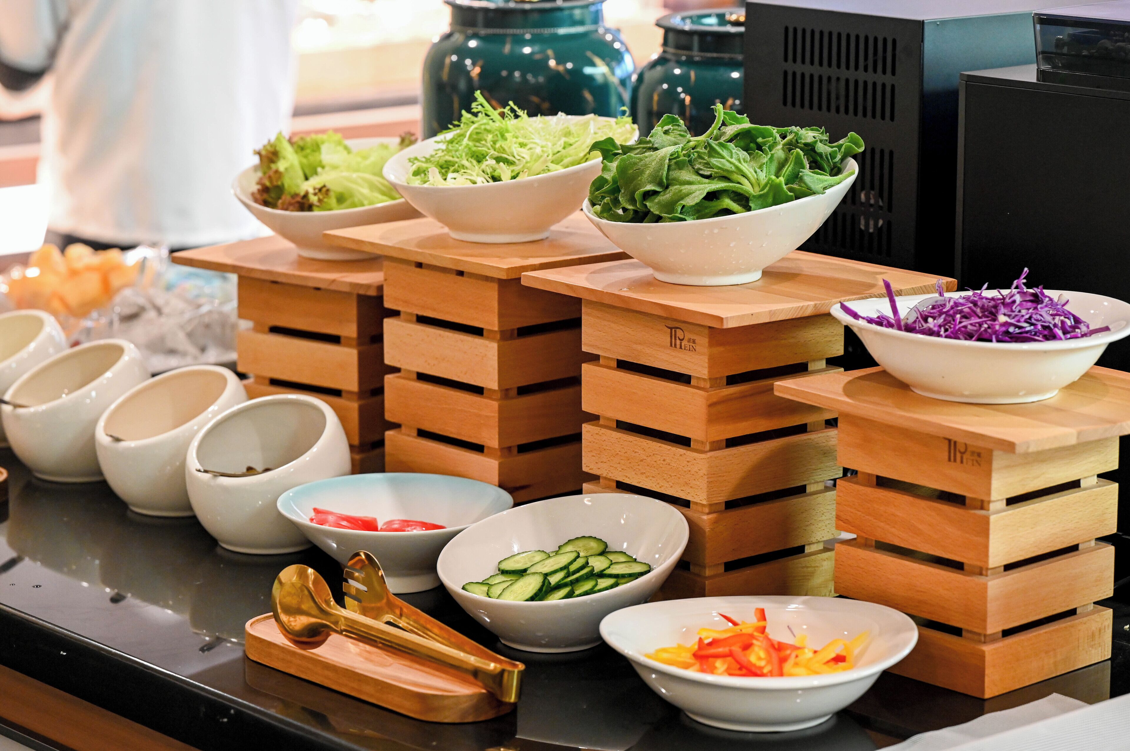 A buffet setup with various bowls of food on wooden stands.