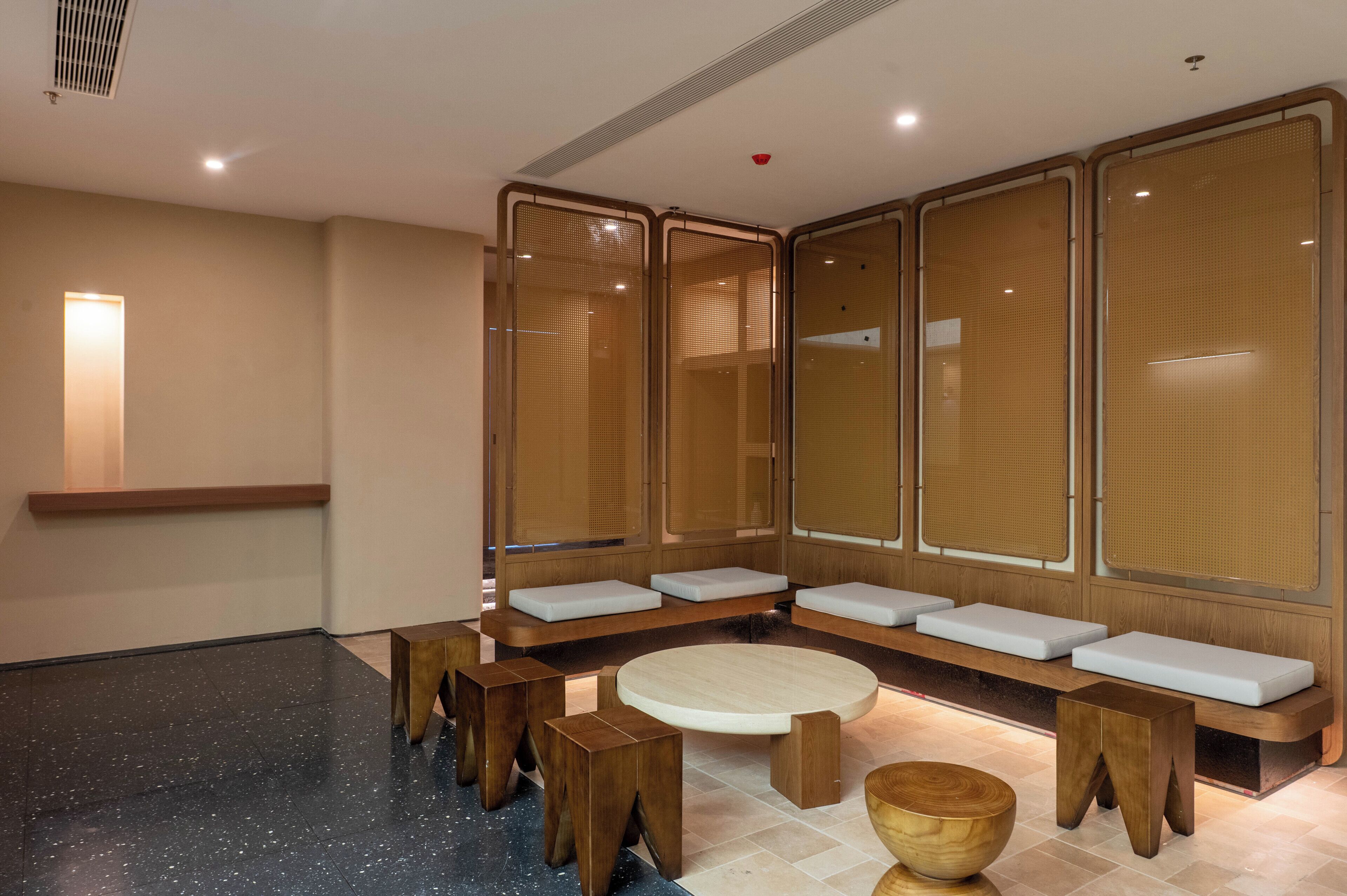 Un moderno spa con bancos de madera, una mesa redonda y un amplio ventanal.