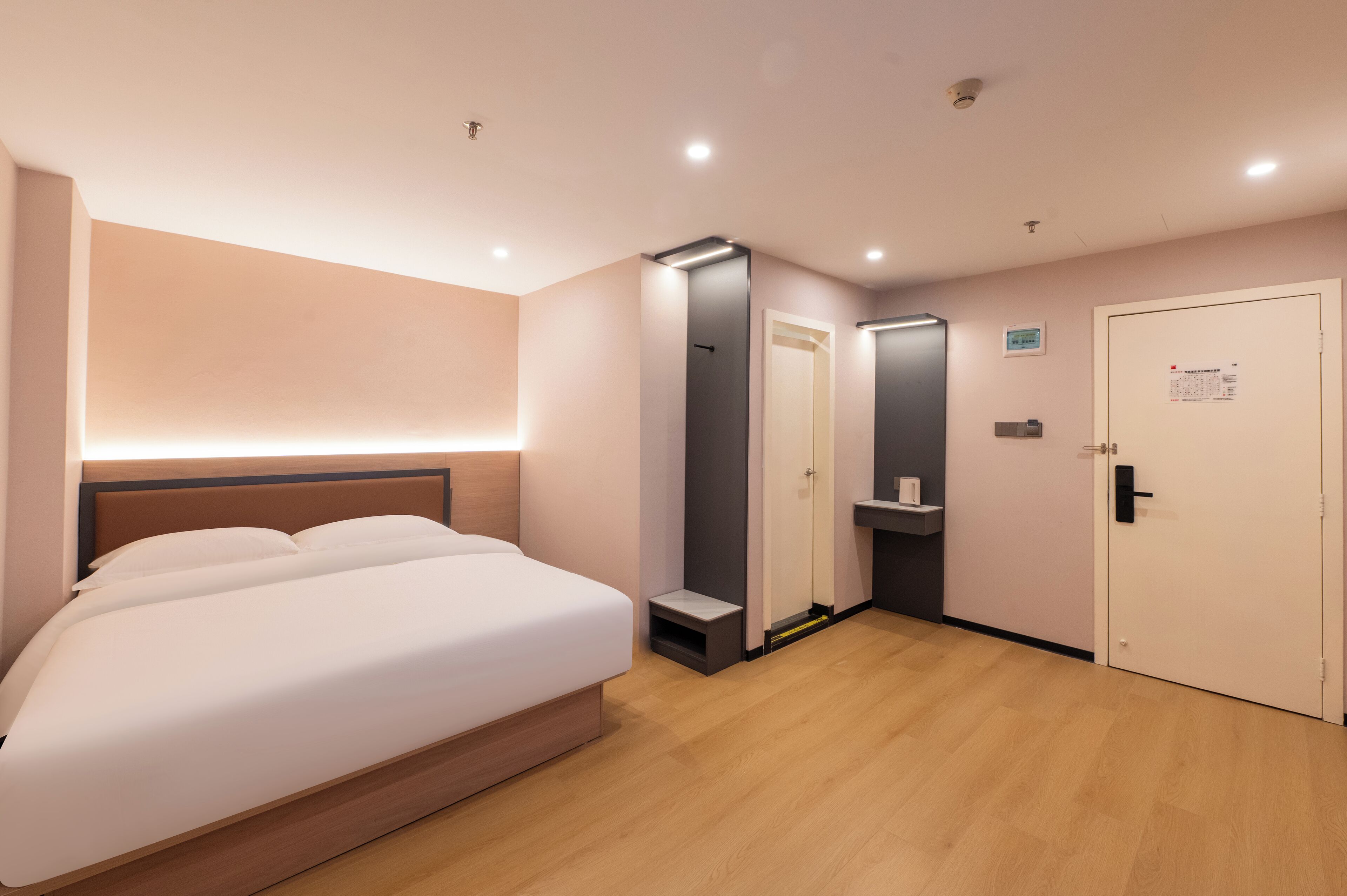 Ein modernes Hotelzimmer mit einem großen Bett, einem eingebauten Kleiderschrank, einem kleinen Badezimmer und einer Tür mit einem Kalender.
