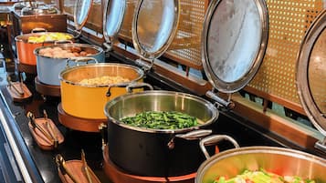A buffet with various food items in large pots, arranged on a counter with metal serving utensils.