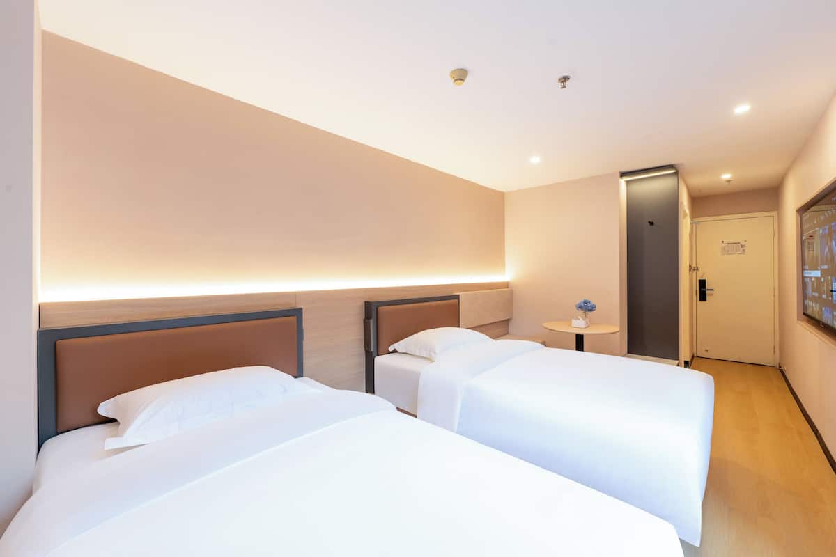 Ein Hotelzimmer mit zwei Betten, einem kleinen Tisch und einer Tür zu einem Badezimmer.