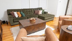 A modern living room with a sectional sofa, a coffee table, and leather armchairs. - Happiness at NO-CHARGE in walkaway Akard Travelbae Luxe Haus (Dallas)