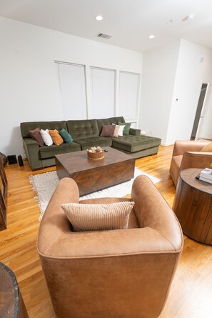 Een moderne woonkamer met een modulaire bank, een salontafel en leren fauteuils.