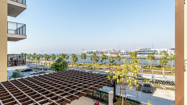 Varanda com pérgola, vista para o porto de embarcações e área de estacionamento com carros.