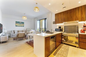 Una cocina moderna con armarios de madera, horno integrado y zona de comedor con sofá y mesa.