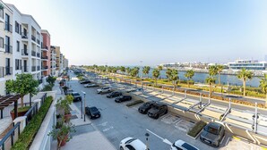 Uma área de estacionamento com vários carros, vista para a orla marítima e uma fileira de edifícios modernos.
