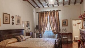 A bedroom with a wooden ceiling, a bed, a desk, and a chair. - PALAZZO PALESA B&B dimora storica (San Casciano dei Bagni)