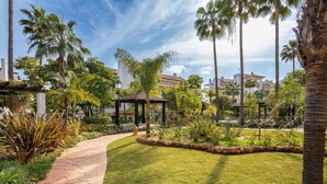 A paved pathway, a gazebo, and palm trees in a landscaped garden area.
