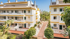 Un edifici residencial de diverses plantes amb balcons, un camí central i vegetació als voltants.