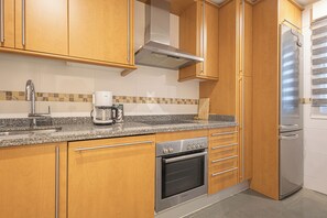 Una cocina con armarios de madera, un horno de acero inoxidable, una cafetera y un refrigerador.