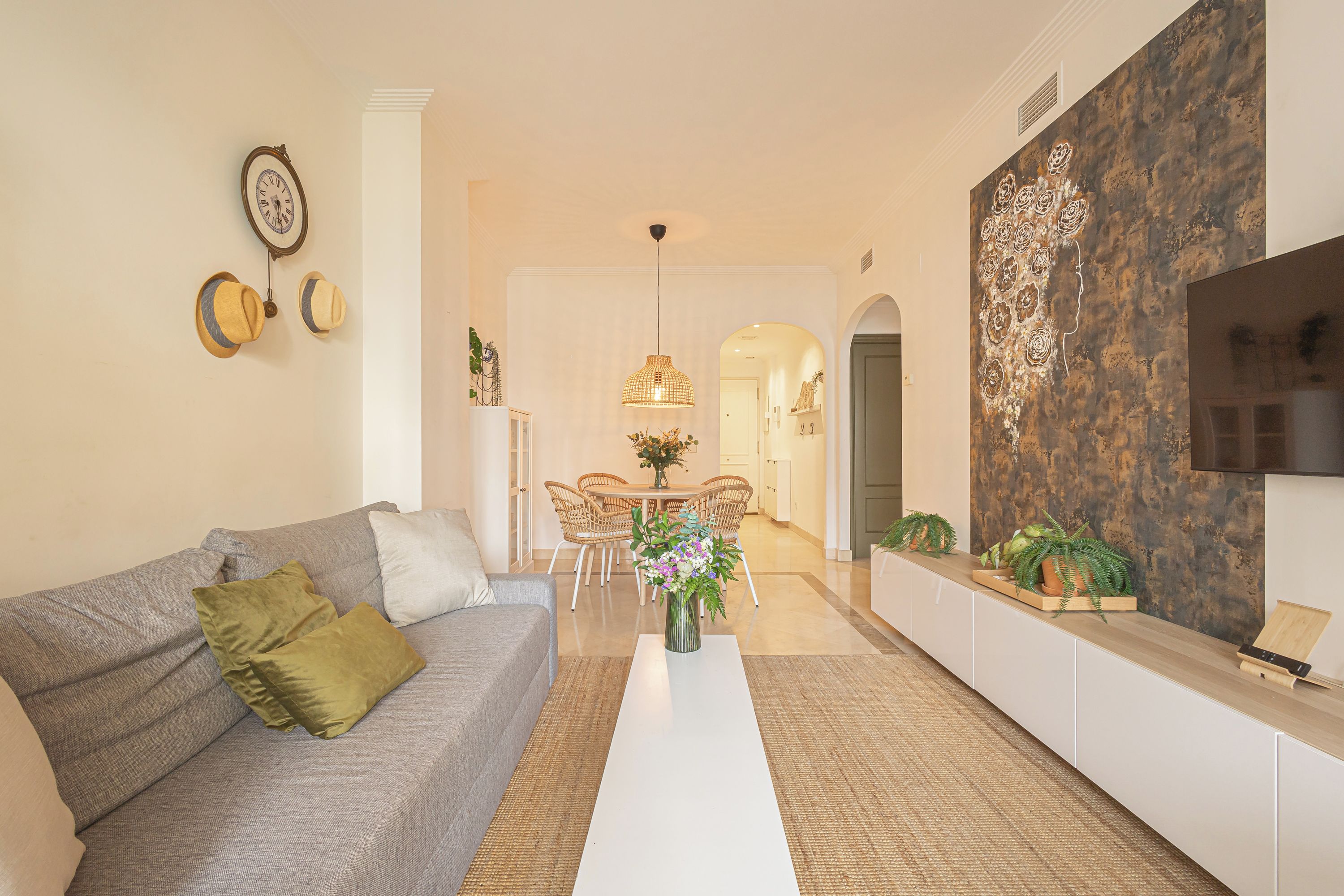 A modern living room with a sofa, coffee table, and a dining area with chairs and a table.