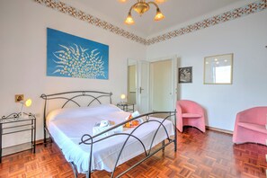 Une chambre à coucher avec un lit, des tables de chevet, une chaise, un tableau et une porte.
