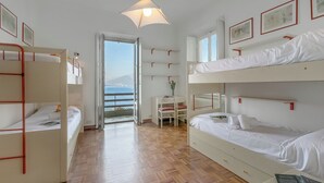 A room with bunk beds, a desk, a chair, and a view of the sea. - Villa Incanto Sul Lago: Lakefront, Garden & Balconies (Laveno Mombello)