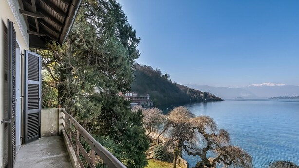 A balcony with a view of a lake, trees, and distant mountains. - Villa Incanto Sul Lago: Lakefront, Garden & Balconies (Laveno Mombello)