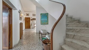 Una escalera con barandilla de madera, piso de baldosas y un cuadro colgado en la pared.