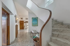 A staircase with a wooden handrail, a tiled floor, and a wall-mounted painting. - Villa Incanto Sul Lago: Lakefront, Garden & Balconies (Laveno Mombello)