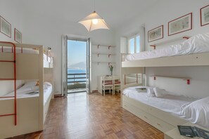 Ein Zimmer mit Stockbetten, einem Schreibtisch, einem Stuhl und Meerblick.
