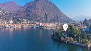 A lake with a mountain in the background and a town with buildings along the shore. - Villa Incanto Sul Lago: Lakefront, Garden & Balconies (Laveno Mombello)