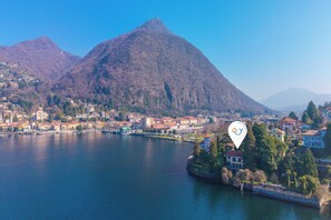 A lake with a mountain in the background and a town with buildings along the shore. - Villa Incanto Sul Lago: Lakefront, Garden & Balconies (Laveno Mombello)