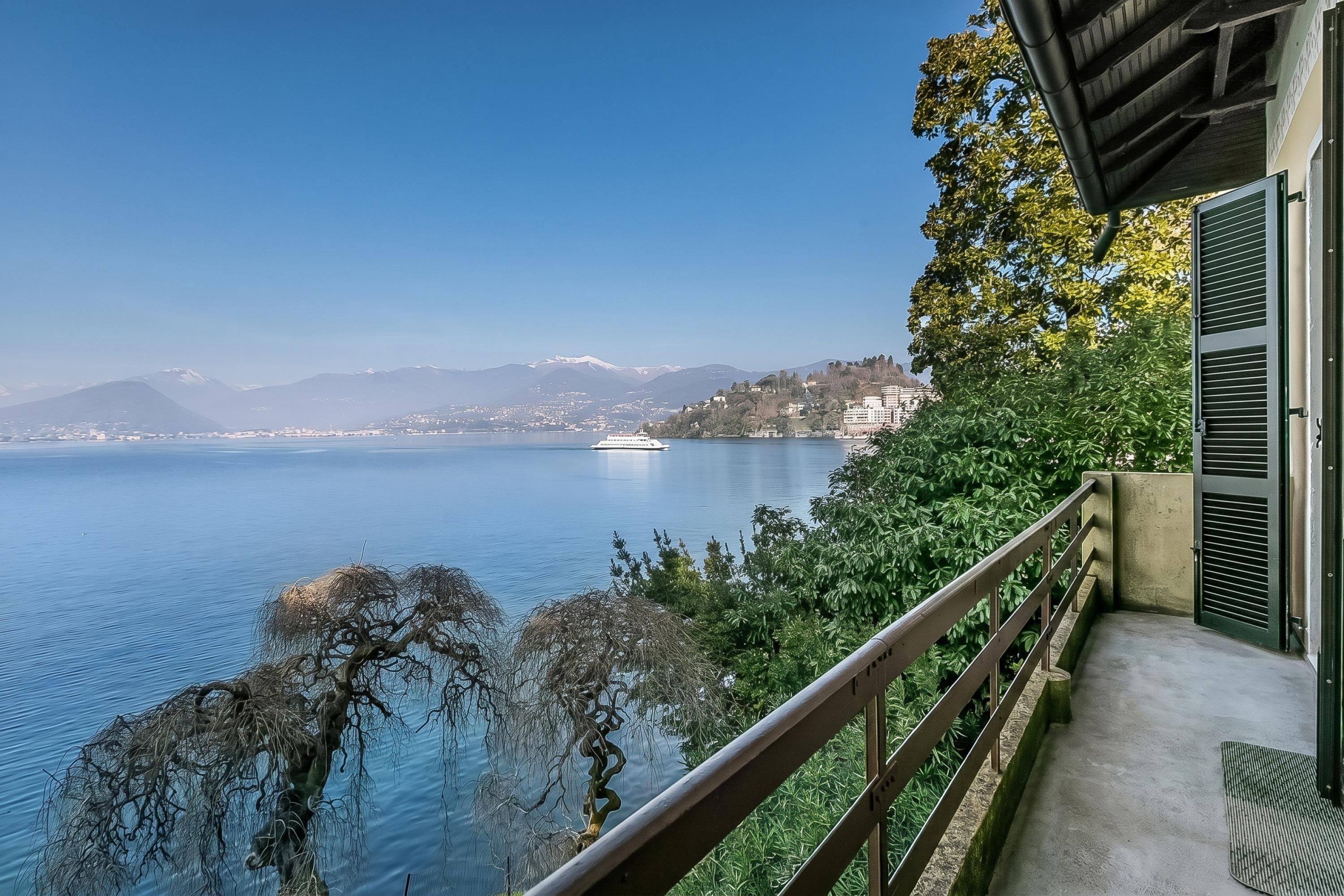 Uma varanda com vista para um lago, montanhas e um cruzeiro.