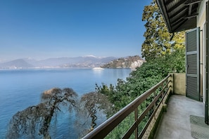 Ein Balkon mit Blick auf einen See, Berge und ein Kreuzfahrtschiff.