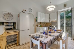 Eine Küche mit Esstisch für vier Personen, einem Kühlschrank und einer Wanduhr.