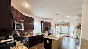 Una cocina moderna con armarios de madera oscura, encimeras de granito, electrodomésticos de acero inoxidable y una isla grande.