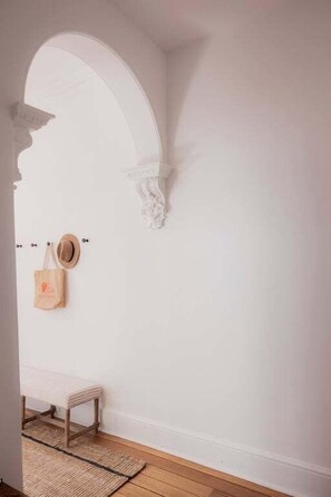 A room with a white wall, a wooden bench, a woven rug, and a hat hanging on the wall. - Elgin House Est. 1904 (Hobart City)