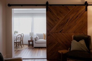 A room with a sliding door leading to a dining area, a sofa, and a wooden accent wall. - Elgin House Est. 1904 (Hobart City)