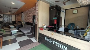 A reception area with a checkered floor, a reception desk, seating area with sofas, and a stone wall. - New Holiday Inn Hotel (Ajmer)