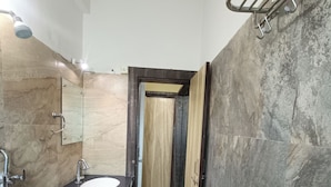 A bathroom with a sink, mirror, shower, and a towel rack. - New Holiday Inn Hotel (Ajmer)