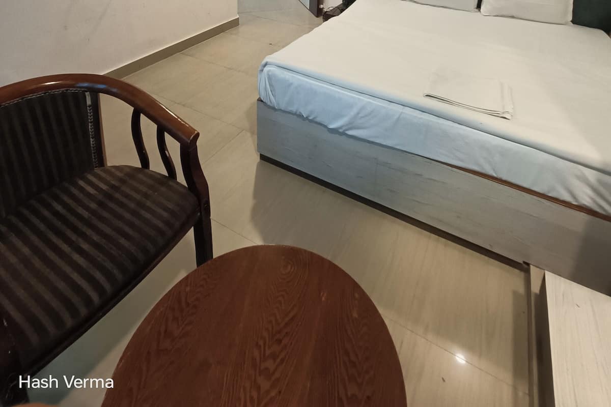 Une chambre d’hôtel avec un lit, un téléviseur fixé au mur, un ventilateur de plafond et un tableau représentant une scène nocturne.