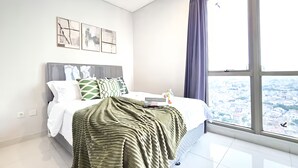 Ein modernes Schlafzimmer mit großem Fenster, einem ordentlich bezogenen Bett und Kunstwerken an der Wand.