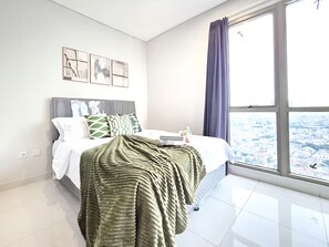 Une chambre moderne avec une grande fenêtre, un lit soigneusement fait et une vue sur la ville.