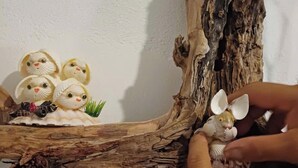 Een stuk drijfhout met een klein figuurtje van een konijn en verschillende kleine dierenfiguurtjes.