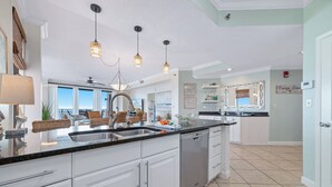 Una cocina moderna con armarios blancos, una isla grande e iluminación colgante.