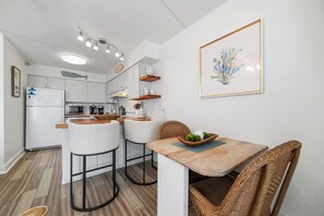Eine moderne Küche mit weißen Schränken, einem Holztisch und Barhocker.