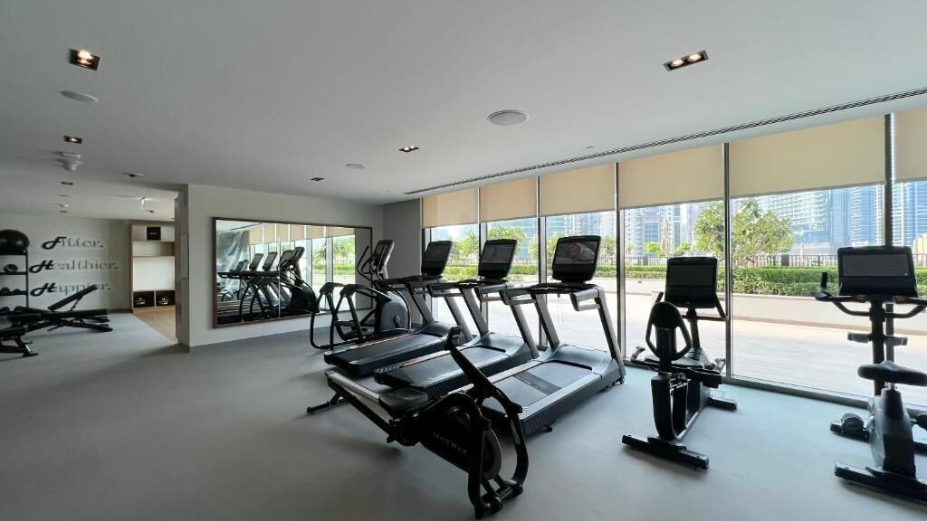 A modern gym with treadmills, stationary bikes, and a large mirror reflecting the space.