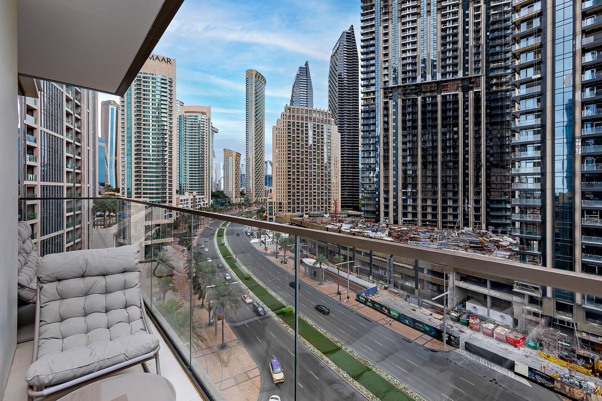 A high-rise building with multiple floors, large windows, and a view of a busy road with cars.
